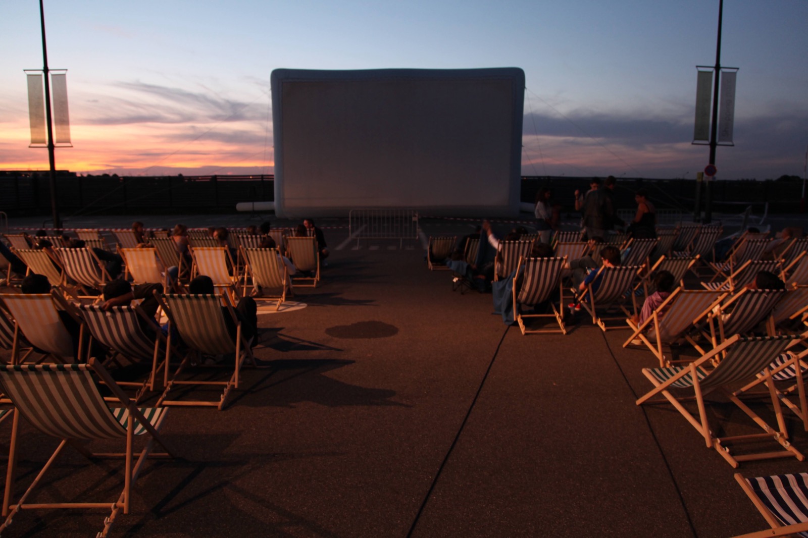 Séance de cinéma en plein air clé en main : écran gonflable Hallucine, transats et public